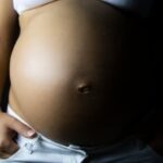 Pregnancy Cravings Image of a pregnant woman with a smile on her face satisfying her PREGNANCY CRAVINGS with a plate of pickles and ice cream