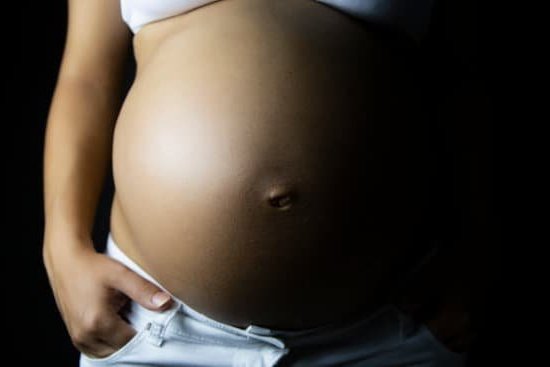 Image of a pregnant woman with a smile on her face satisfying her PREGNANCY CRAVINGS with a plate of pickles and ice cream