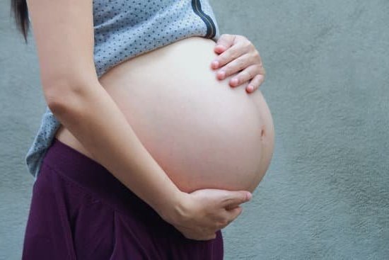 Cramping Early Pregnancy Photo of pregnant woman holding her belly with the text: Dealing with cramping early pregnancy included in the image description