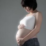 Pregnancy Cramps Photo of woman holding her abdomen with the text: 'Managing Pregnancy Cramps'