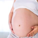 Cramping in Early Pregnancy Image of pregnant woman experiencing cramping in early pregnancy