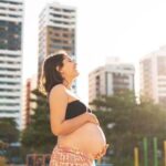 Is Heartburn a Sign of Pregnancy Image of a happy pregnant woman with a hand on her heart, possible sign of heartburn in pregnancy
