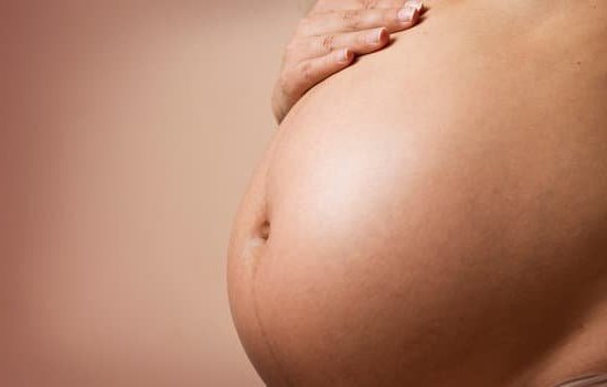 Image of a pregnant woman holding her lower back, experiencing back pain early in pregnancy