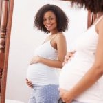 Cramping During Early Pregnancy Image of a pregnant woman holding her stomach, experiencing cramping during early pregnancy